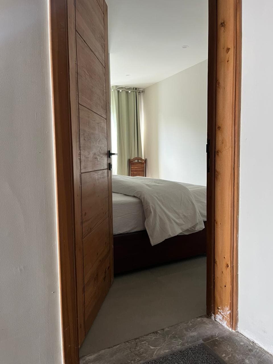 View into the hotel room through the solid wood entrance door at MYG Nathiagali