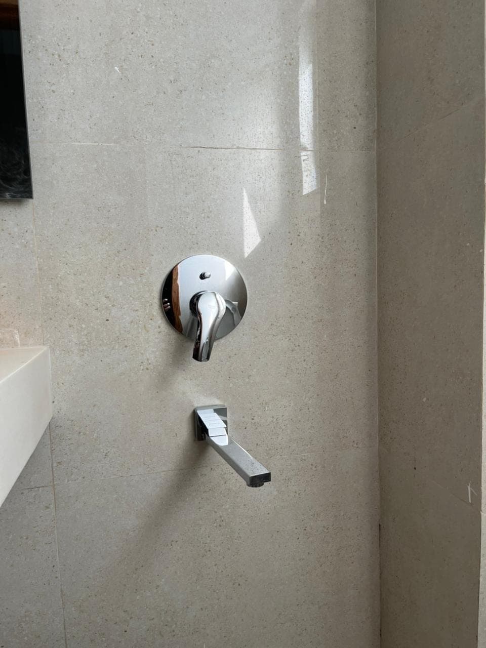Chrome shower mixer and spout on stone-effect tiles in the hotel room en-suite in Nathiagali