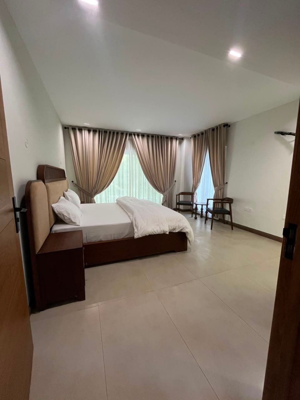 Double bedroom with window seating and full-height curtains in the three-bedroom apartment in Nathiagali