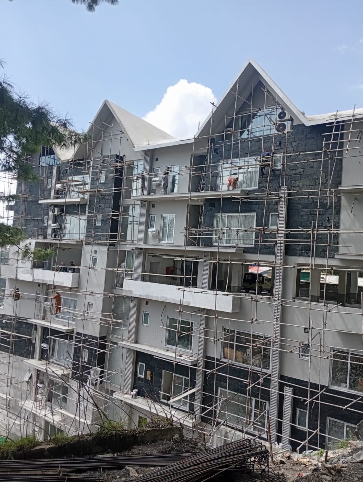 Workers fitting stone cladding on the front elevation of MYG Nathiagali apartments near Abbottabad