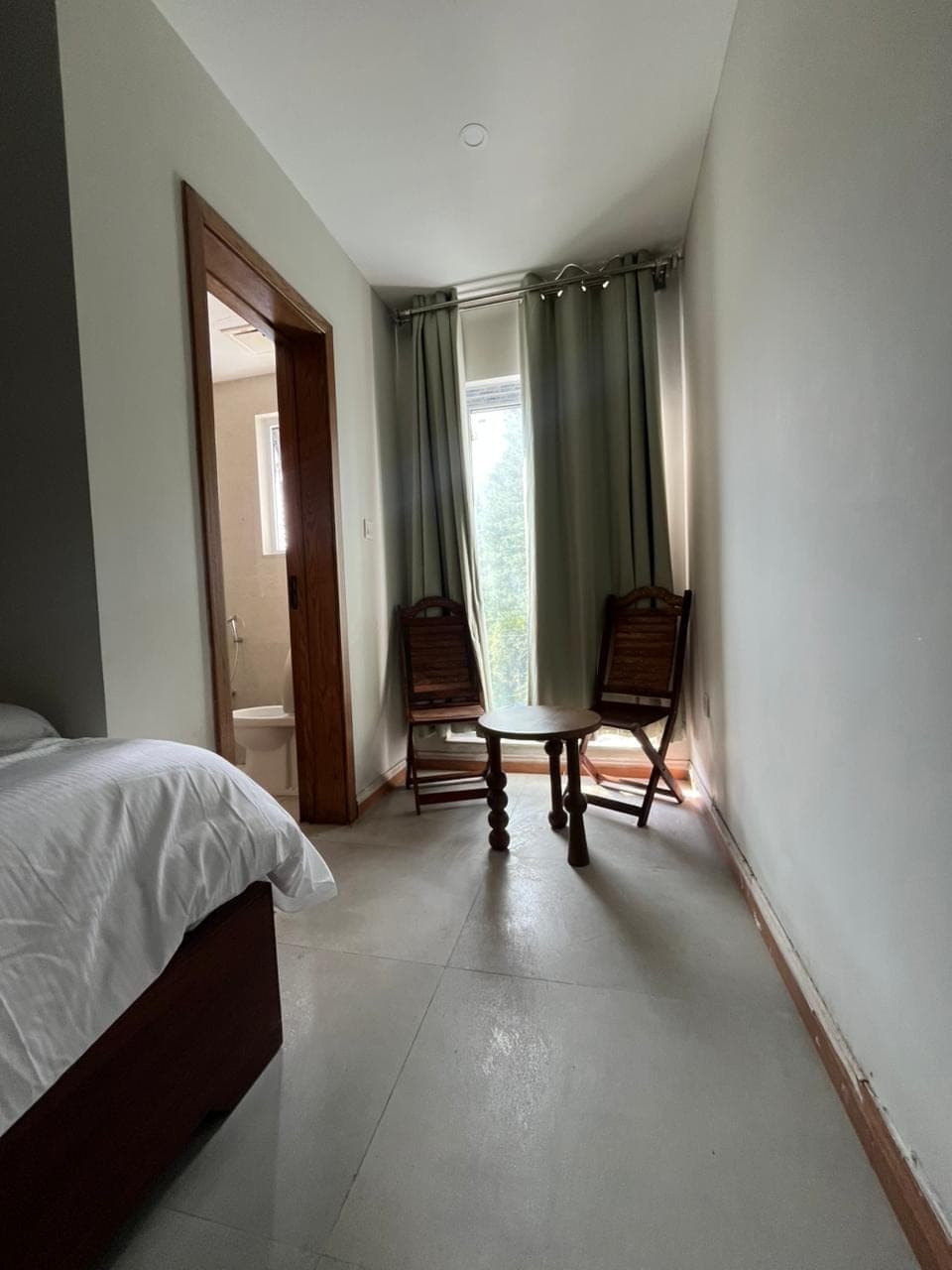 Window sitting nook with two wooden chairs and en-suite bathroom in a Nathiagali hotel room